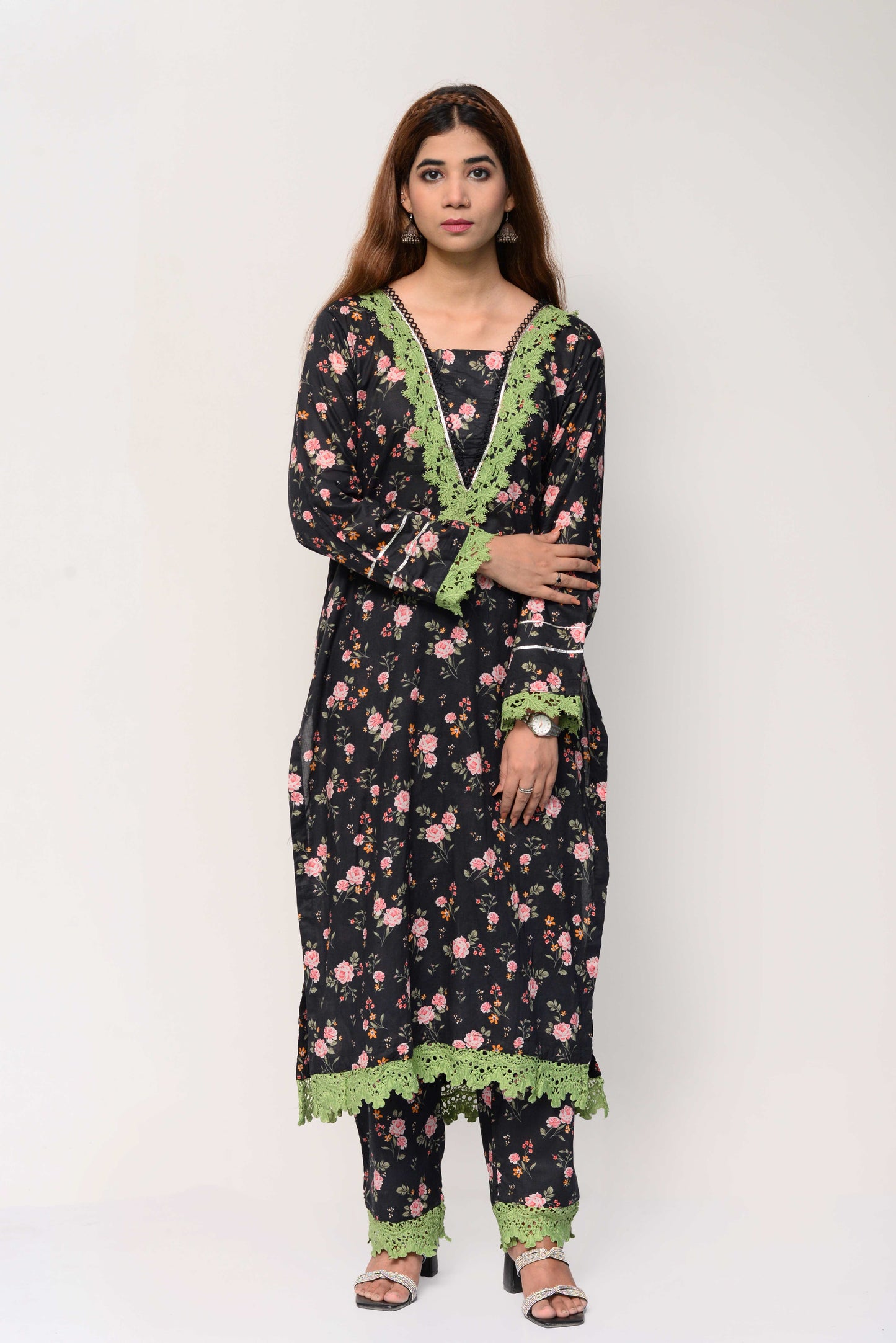 Woman wearing a black floral dress with green accents on a white background