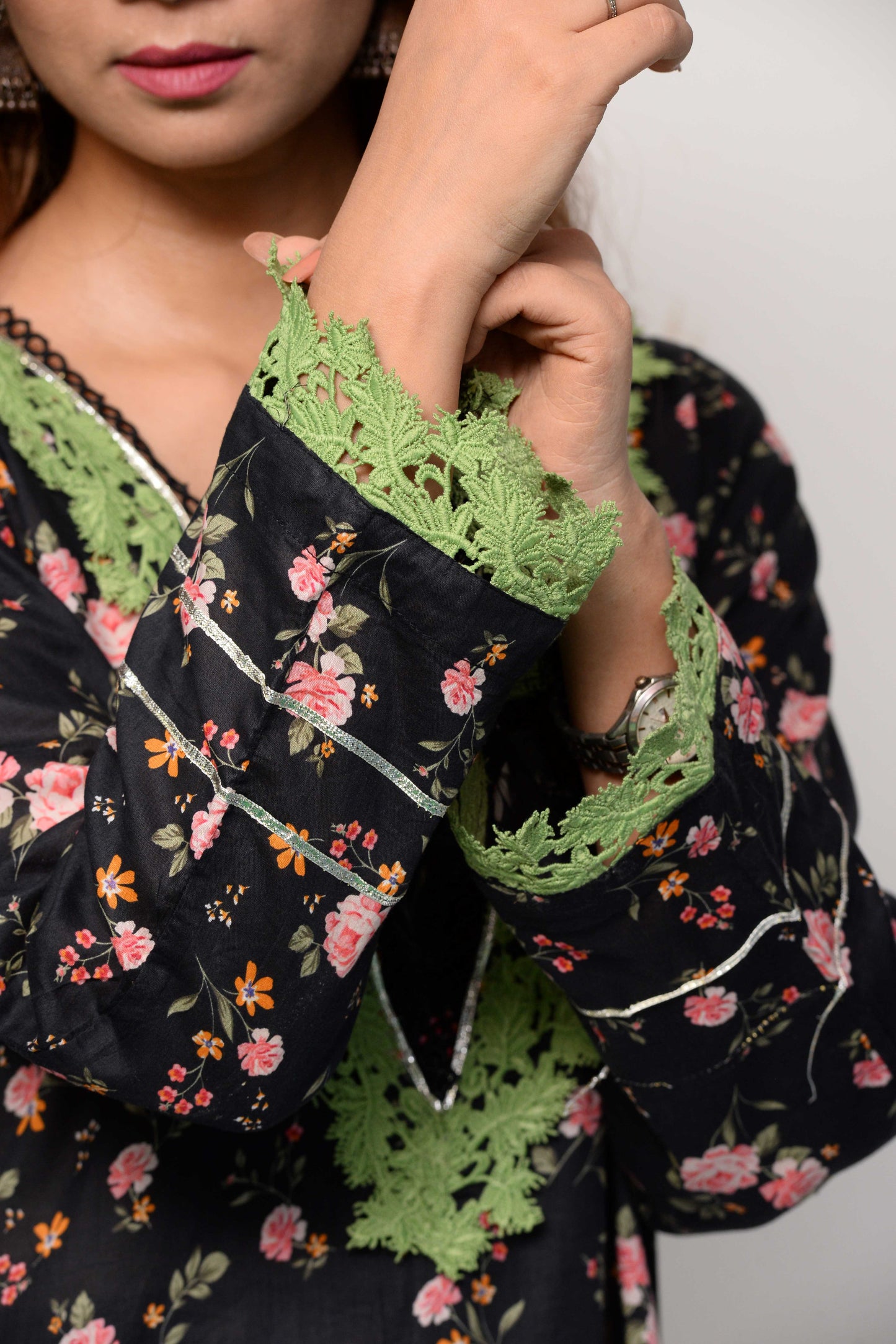 Woman wearing a black floral dress with green accents on a white background