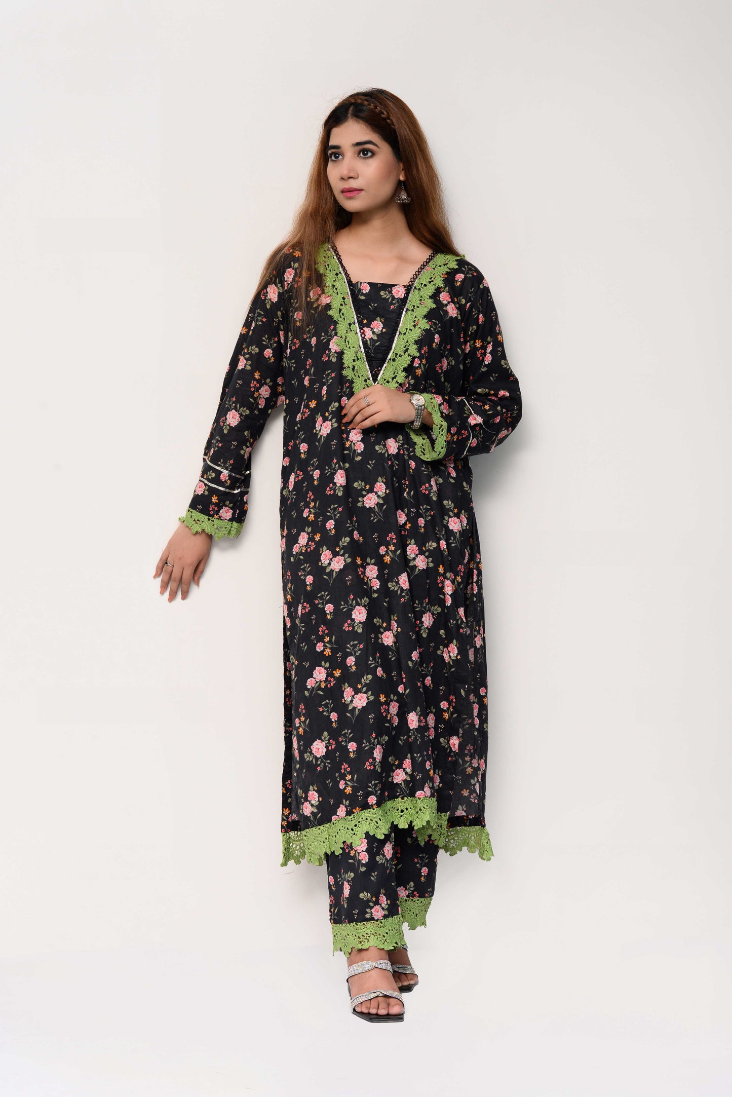 Woman wearing a black floral dress with green accents on a white background