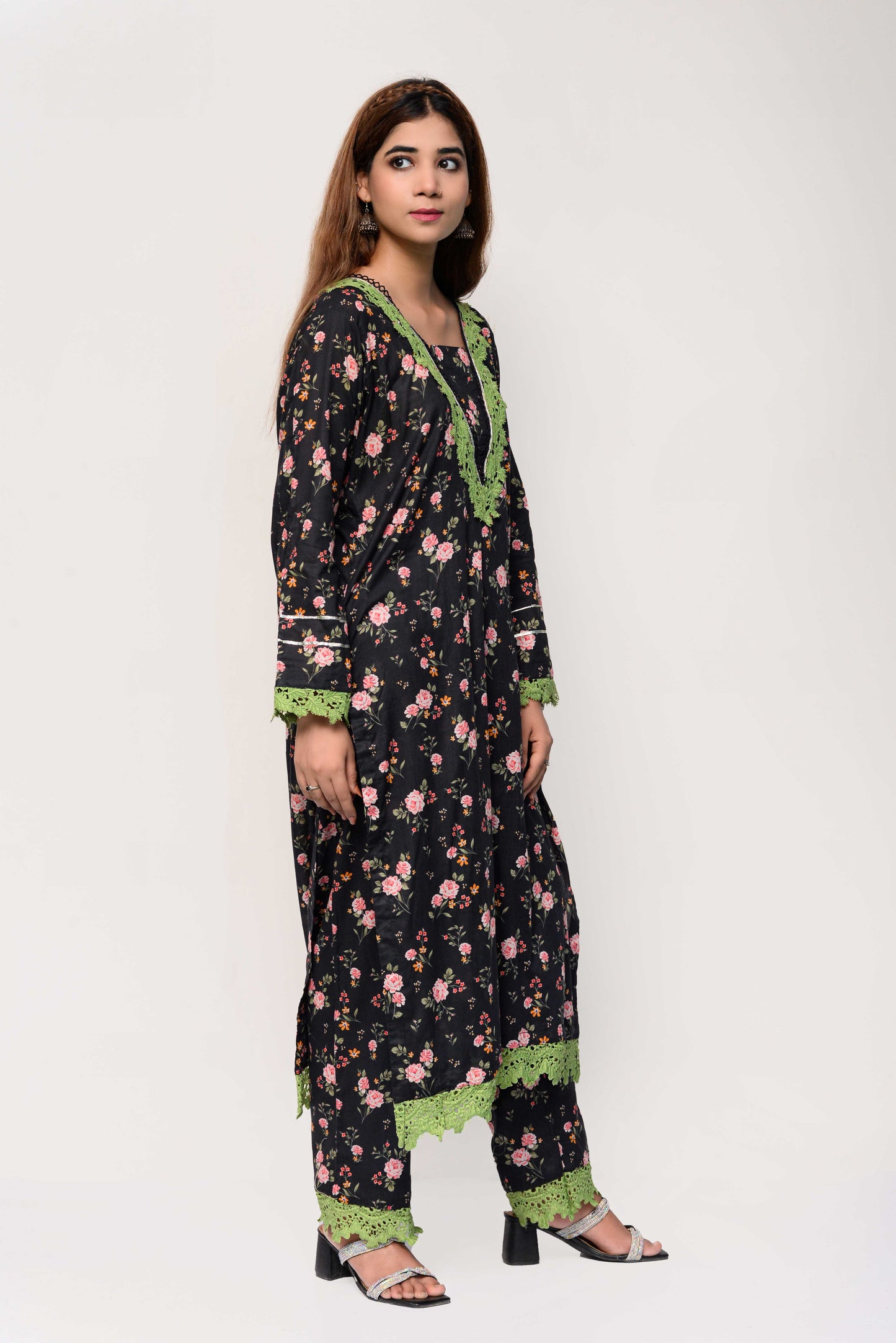 Woman wearing a floral dress with green trim on a white background