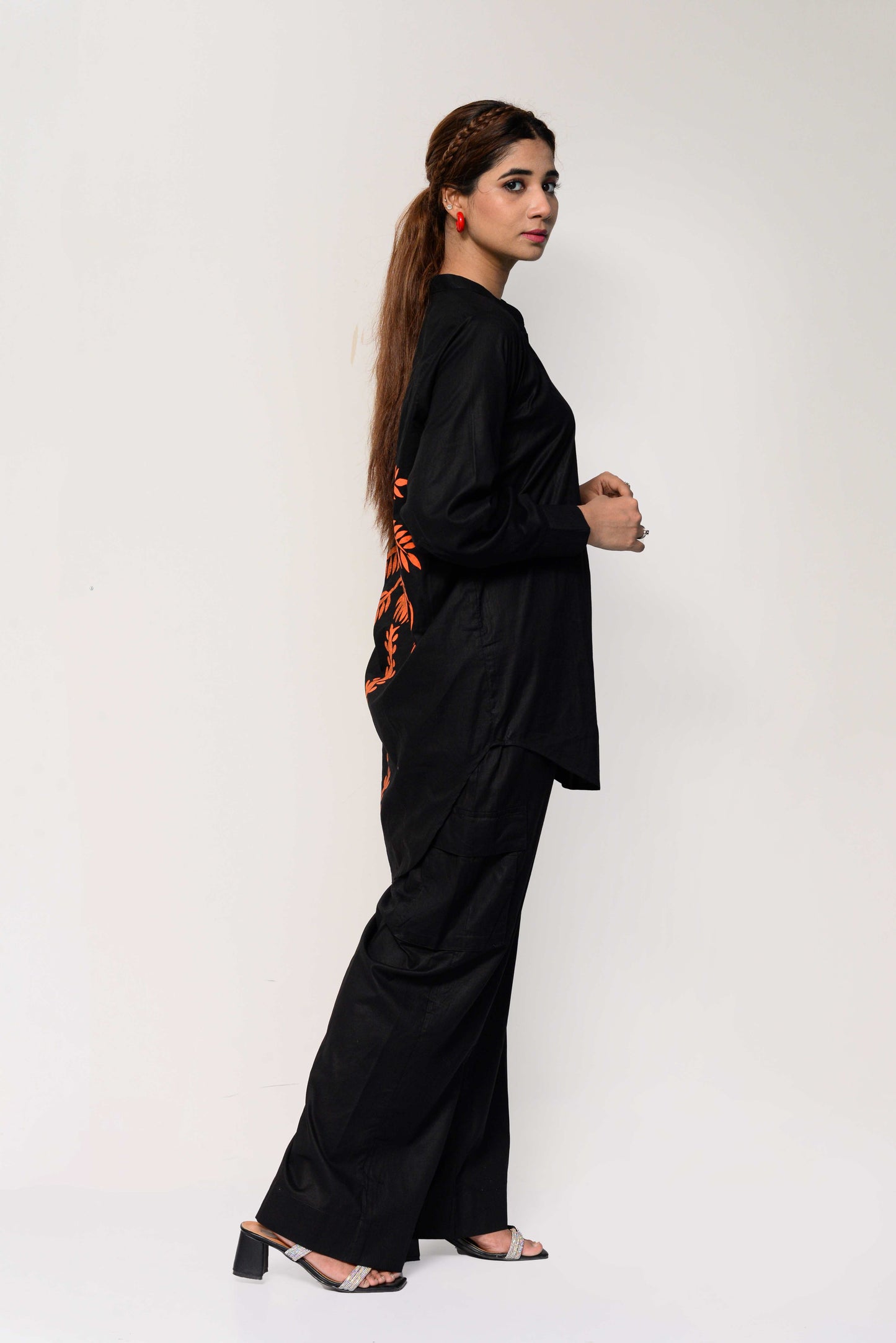 Woman wearing a black outfit with an orange palm tree design on the back against a white background