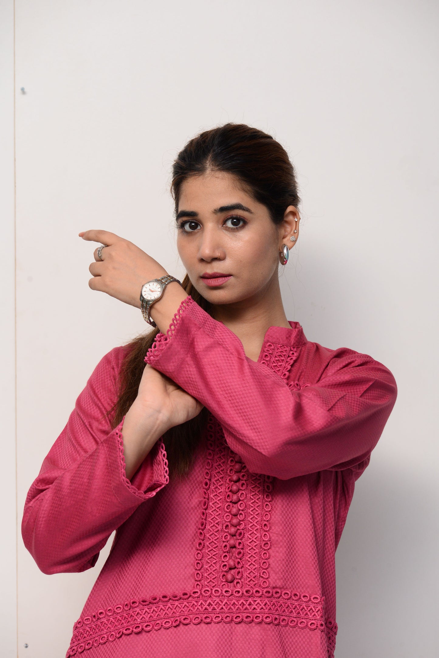 Woman wearing a pink dress with intricate patterns on a white background