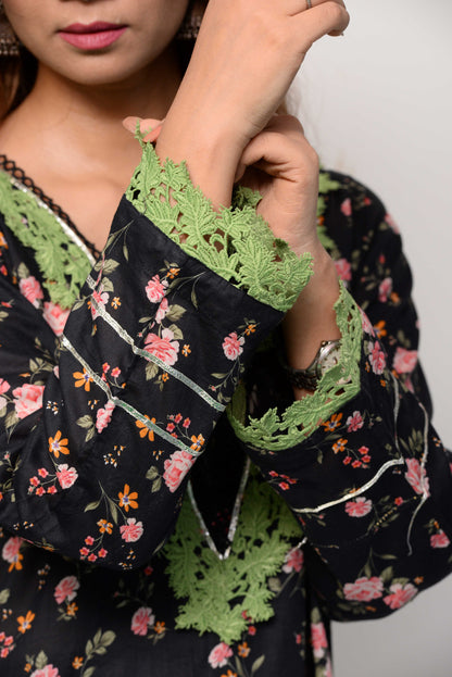 Woman wearing a black floral dress with green accents on a white background