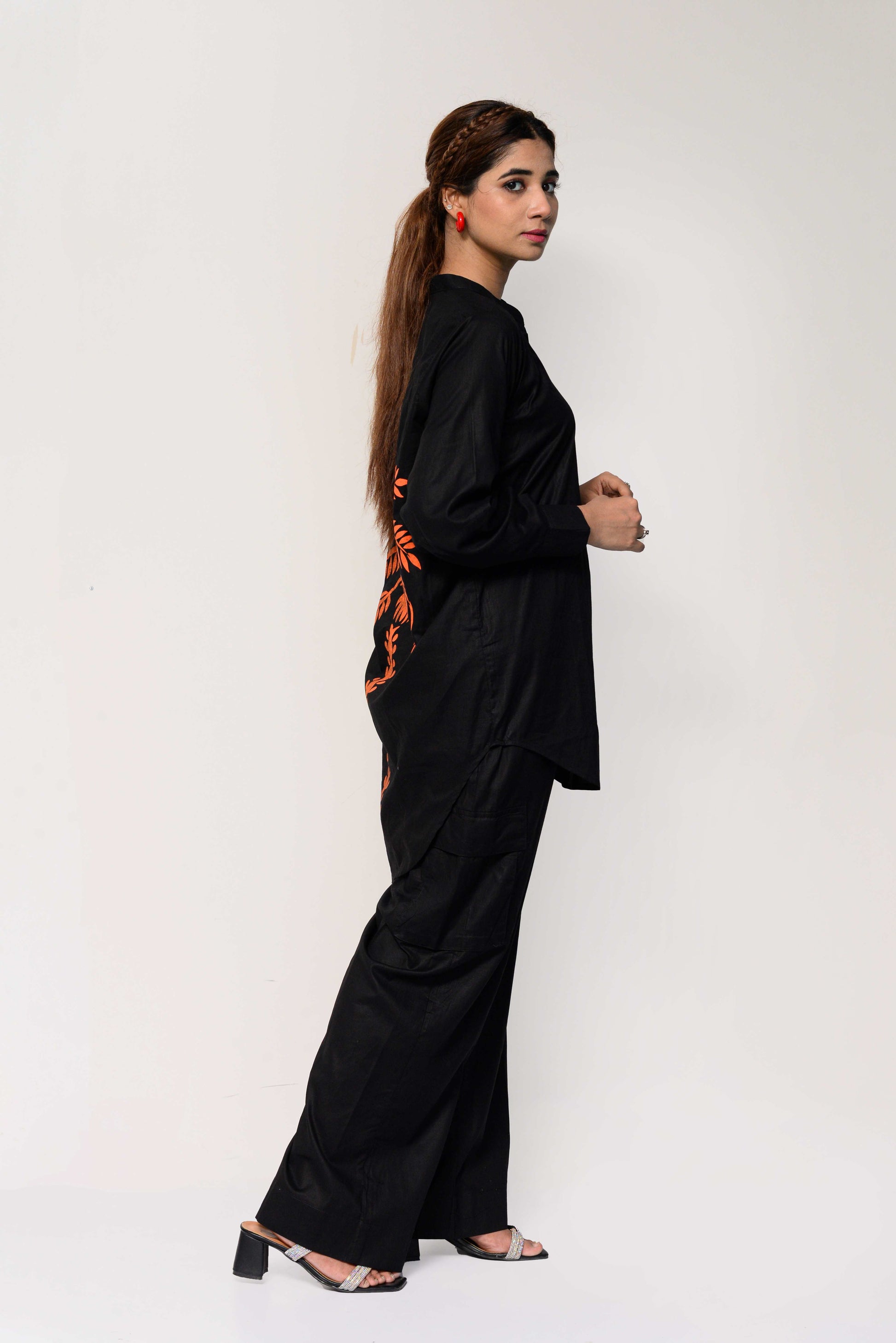 Woman wearing a black outfit with an orange palm tree design on the back against a white background
